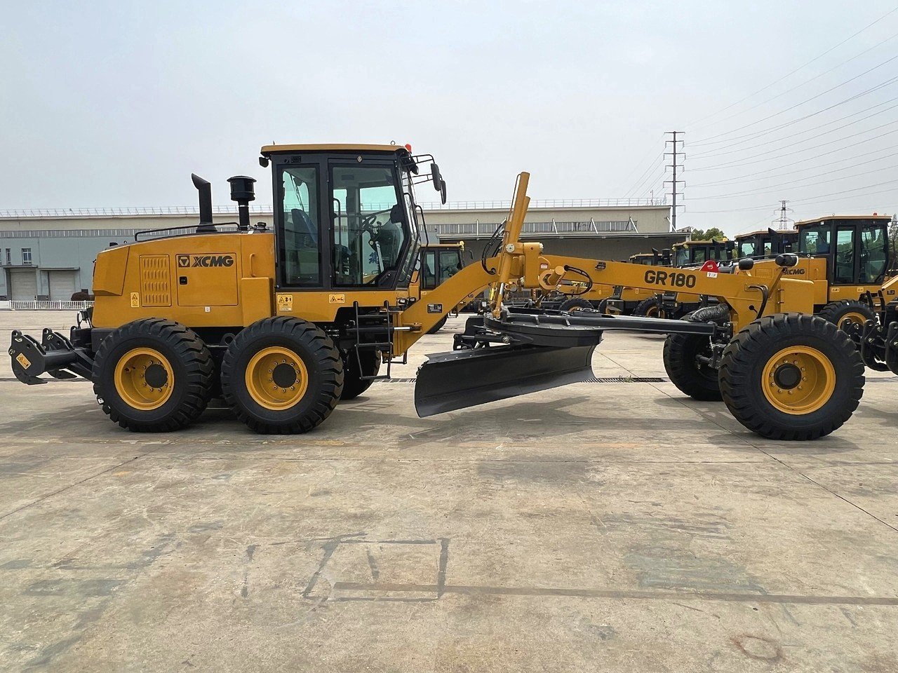 Side view of XCMG GR180 motor grader with blade and articulated frame