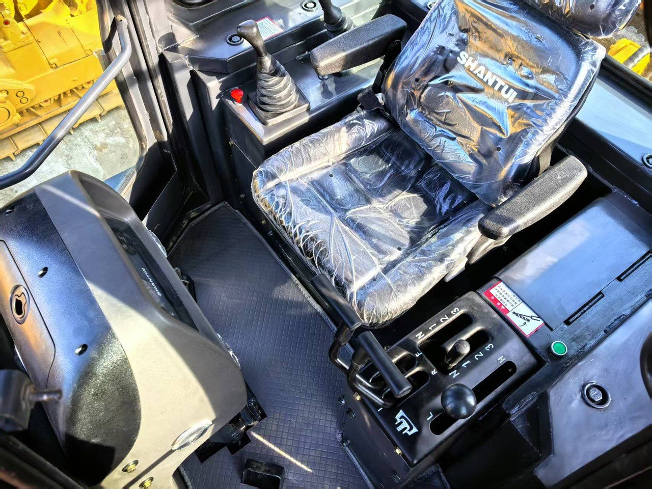 Shantui SD16 bulldozer cab interior showing operator seat, control levers, dashboard, and ergonomic cabin for comfortable operation