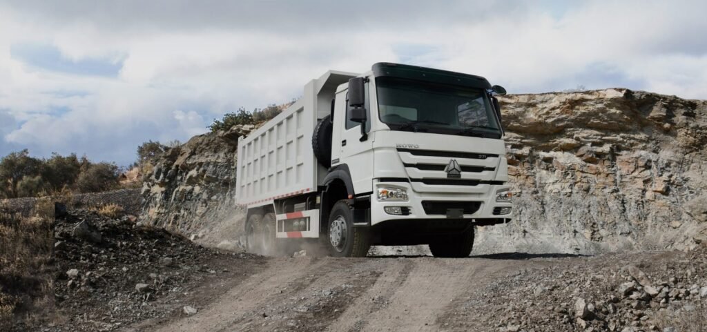 HOWO 371hp dump truck transporting boulders through a rugged mining site.