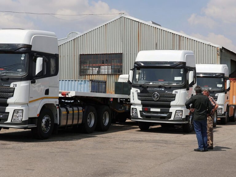White Shacman X3000 tractor trucks parked at a logistics yard with fleet operators