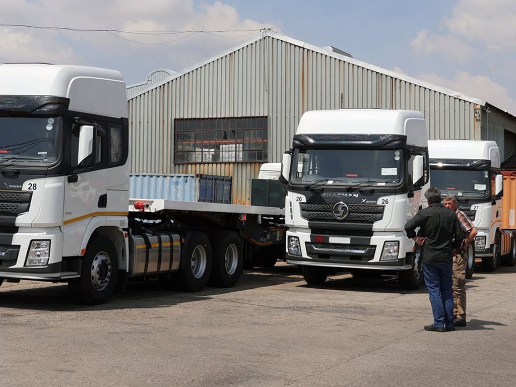 White Shacman X3000 tractor trucks parked at a logistics yard with fleet operators